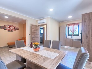 A dining area with a wooden table, chairs, and a vase with flowers. - Villa Amber by Interhome (Pula/Manjadvorci)