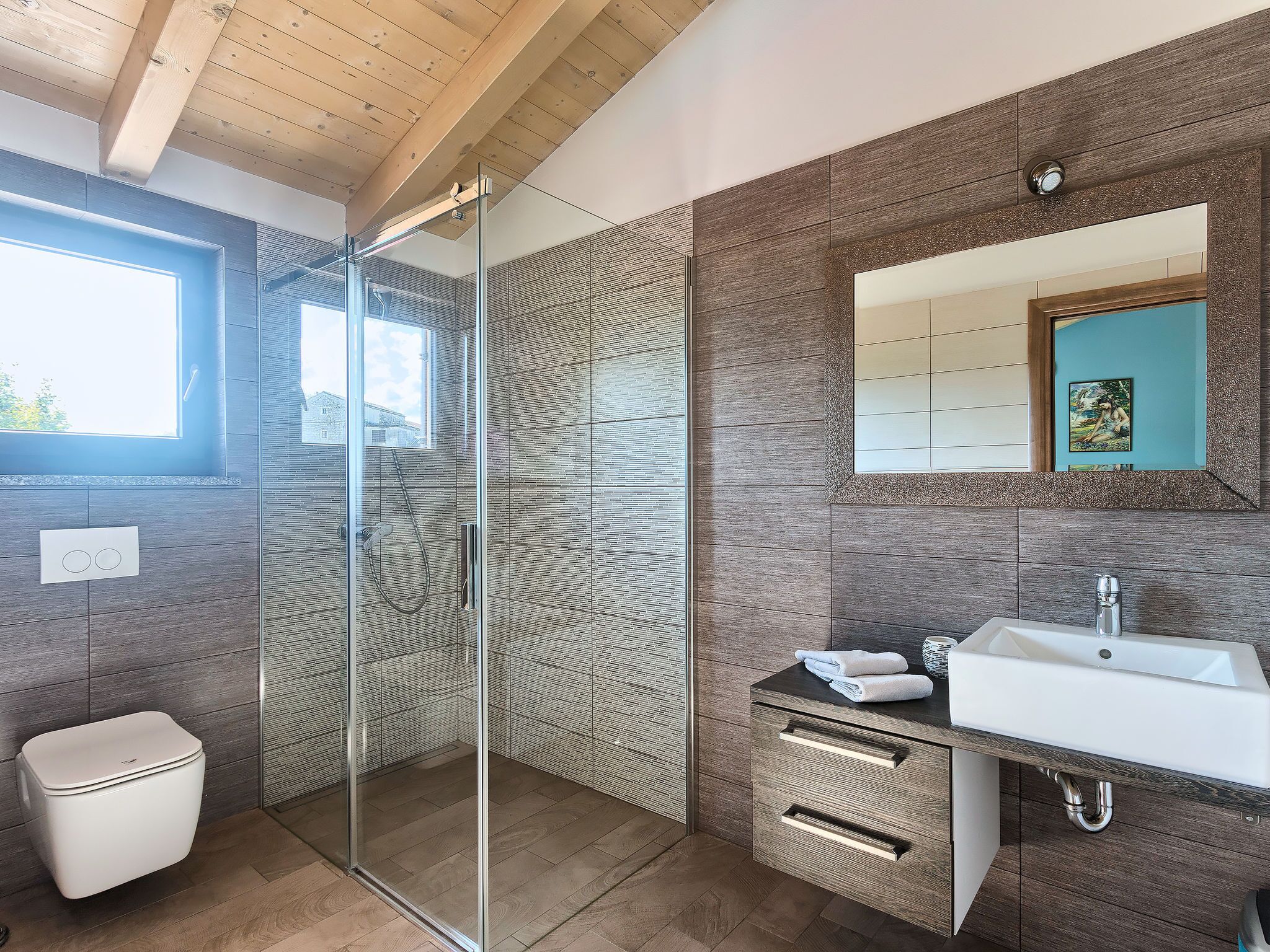 A modern bathroom with a glass shower enclosure, a white sink, and a wooden vanity.