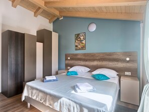 Une chambre d’hôtel avec un lit, une table de chevet, une armoire et un tableau au mur.