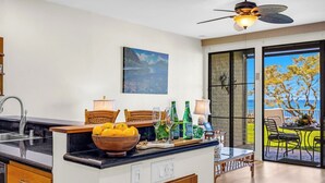 Une cuisine moderne avec un coin repas, un ventilateur de plafond et une vue sur l’extérieur.
