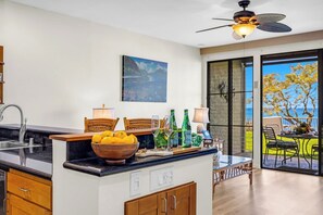 Une cuisine moderne avec un coin repas, un ventilateur de plafond et une vue sur l’extérieur.