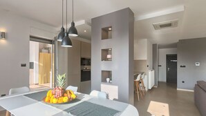 A modern dining area with a white table, black pendant lights, and a fruit centerpiece. - Villa Volimten by Interhome (Pula/Vodnjan)