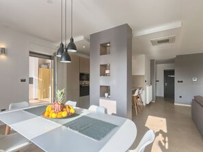 A modern dining area with a white table, black pendant lights, and a fruit centerpiece. - Villa Volimten by Interhome (Pula/Vodnjan)