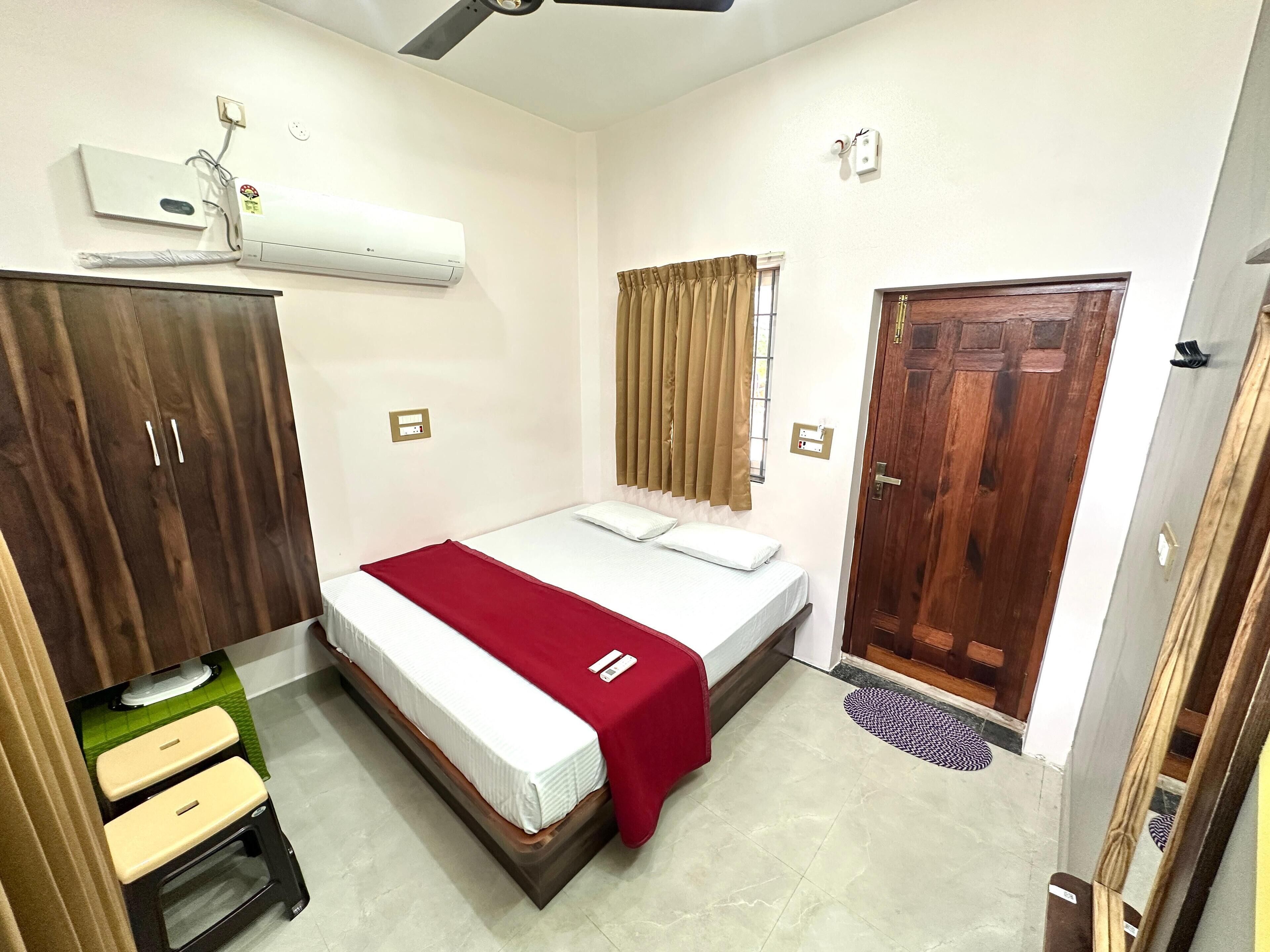 A bedroom with a bed, wardrobe, and an air conditioning unit.