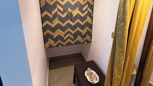 A small, enclosed room with a chevron-patterned wall, a small table with a tray, and a curtain. - OM LINGESWARAN Home Stay Tiruvannamalai (Tiruvannamalai)