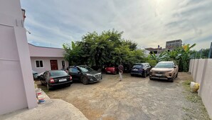 A parking area with several cars, a building, and some greenery. - OM LINGESWARAN Home Stay Tiruvannamalai (Tiruvannamalai)