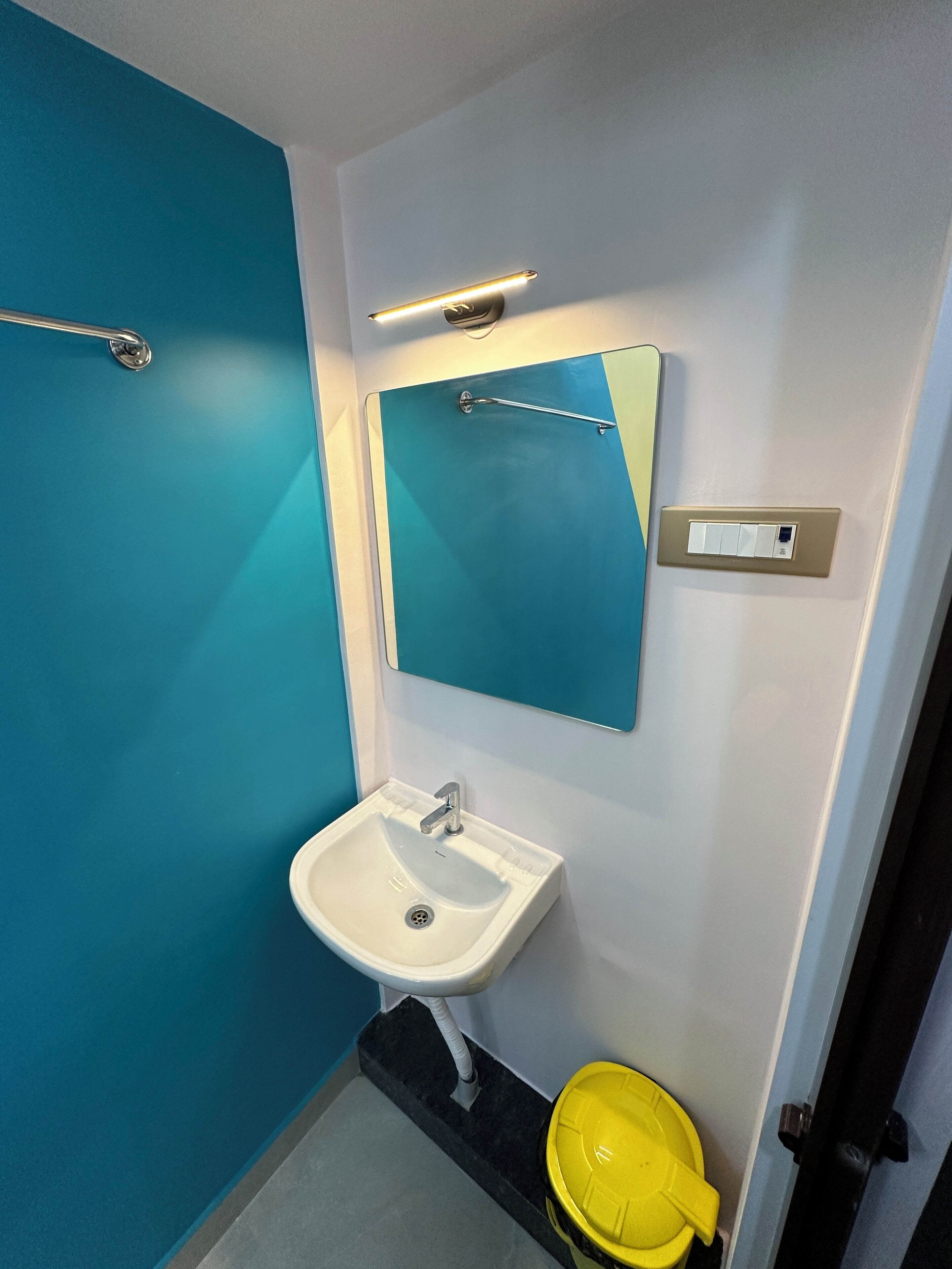 A bathroom with a white sink, a mirror, and a blue wall.