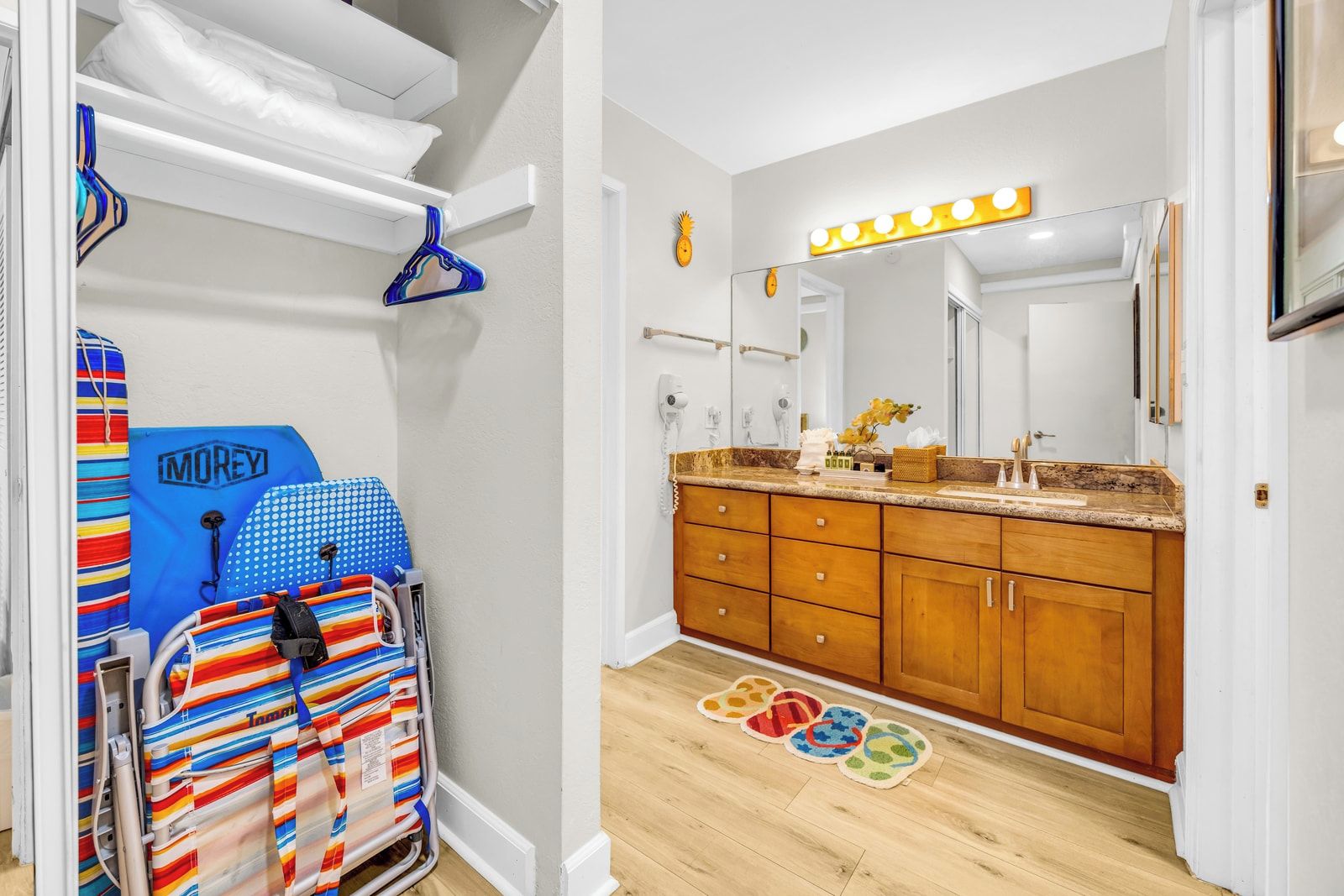 A bathroom with a vanity, a mirror with lights, a towel rack, and a shower area.