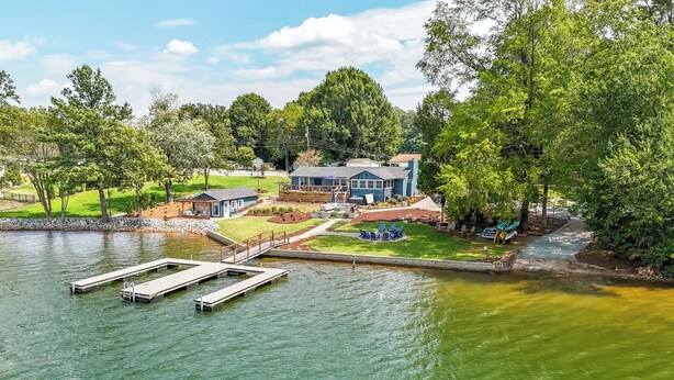 A lakeside property with a dock, a house, and a well-maintained lawn.