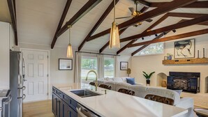 A kitchen with a large island, wooden beams, and pendant lighting.