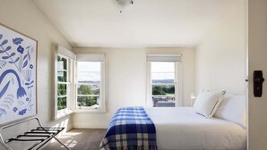 Een slaapkamer met een bed, een raam, een radiator en een kunstwerk aan de muur.