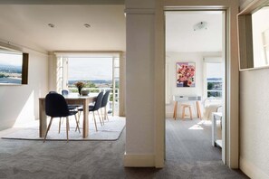 A modern interior with a dining area, a large window with a view, and a hallway leading to a bedroom. - Tennis or Town - Parking and Wifi (Launceston)
