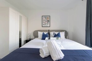 A hotel room with a bed, a nightstand, a framed picture on the wall, and a wardrobe. - 4-Bed Maidstone House Sleeps 8 | Near East Station (Maidstone)