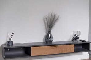 A modern, minimalist console table with a drawer, a vase with decorative branches, and a bicycle.