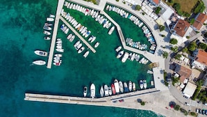 Vista aérea de uma marina com muitos barcos atracados, cercada por edifícios residenciais e uma orla marítima clara.