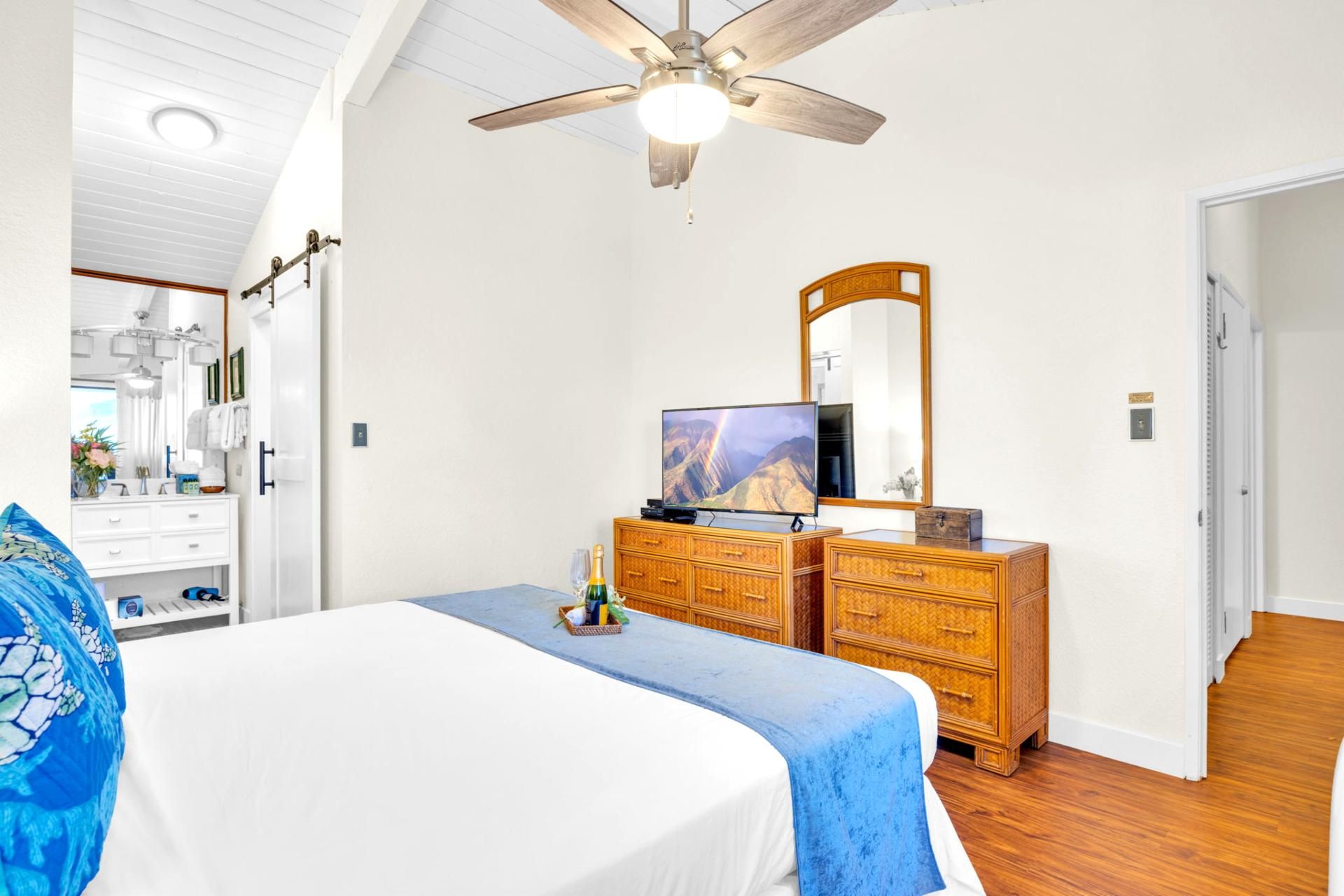A bedroom with a bed, a dresser, a television, and a ceiling fan.