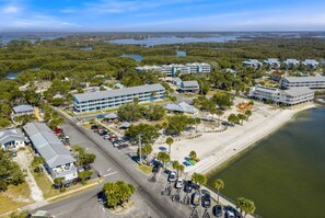 An aerial view of a coastal hotel with multiple buildings, a parking lot, and a beach. - A Wave From It All at Park Place (Cedar Key)