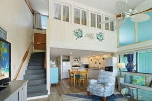 A spacious living area with a staircase, a kitchen, and a dining area. - A Wave From It All at Park Place (Cedar Key)