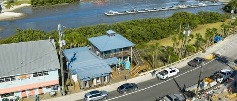 A coastal town with a dock, a restaurant, and a road with vehicles.
