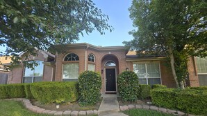 A two-story brick house with a black front door, arched windows, and a well-maintained lawn. - Spacious 5-bedroom house in fantastic DeSoto with AC (DeSoto)