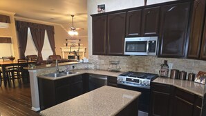 A kitchen with granite countertops, a stainless steel stove, and dark wooden cabinets. - Spacious 5-bedroom house in fantastic DeSoto with AC (DeSoto)