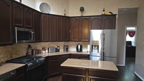 A kitchen with dark wood cabinets, stainless steel appliances, granite countertops, and a built-in oven. - Spacious 5-bedroom house in fantastic DeSoto with AC (DeSoto)