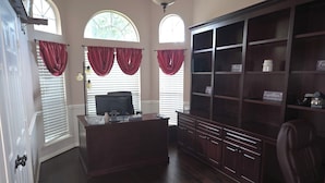 A room with a wooden desk, a computer, and a large bookcase. - Spacious 5-bedroom house in fantastic DeSoto with AC (DeSoto)