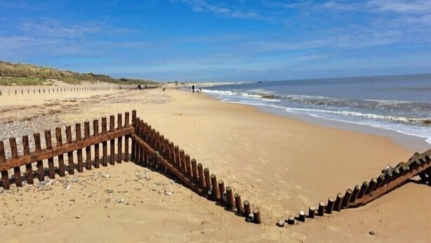 Une plage avec une clôture en bois et un ciel dégagé.