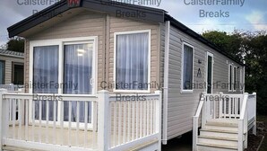 Une maison mobile de plain-pied avec un porche à l’avant et une petite terrasse.