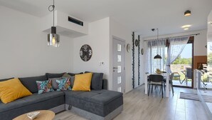 A modern living room with a grey sectional sofa, a small round table, and a dining area with a table and chairs. - House Bronzin by Interhome (Rovinj/Kanfanar)