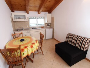 Eine kompakte Küche mit Esstisch, Stühlen, einer Couch und einem Kühlschrank.