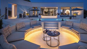 Un espacio exterior moderno con piscina, mobiliario y una entrada bien iluminada.