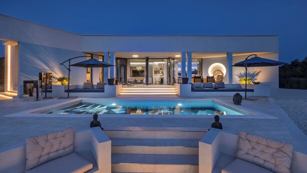 Una casa moderna con piscina, mobiliario exterior y una escalera que lleva a la entrada.