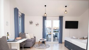 Eine moderne Wohnung mit Essbereich, Sofa, Fernseher und einem Balkon mit Blick.