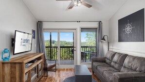 Una sala de estar moderna con un sofá gris, mueble de entretenimiento de madera y un televisor.