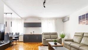 Ein modernes Wohnzimmer mit Sofa, Couchtisch, Fernseher und Küchenzeile.