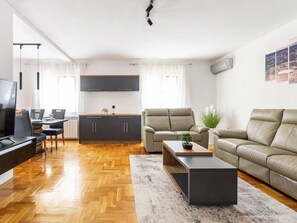 A modern living room with a sofa, coffee table, TV, and kitchen area. - Apartment DP by Interhome (Bokordici)