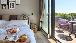 A hotel room with a bed, breakfast tray, framed pictures, and a balcony with a table and chair. - Villa Grande by Interhome (Poreč/Tar)