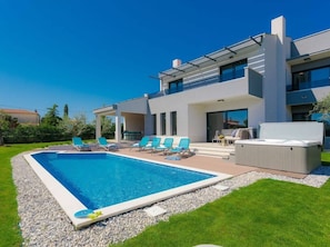 Une maison moderne à deux étages dotée d’une piscine, d’un espace salon extérieur et d’un patio couvert.