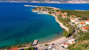 An aerial view of a coastal town with a beach, clear blue waters, and a mountainous backdrop. - Apartment Tunera - 2 by Interhome (Krk/Šilo)