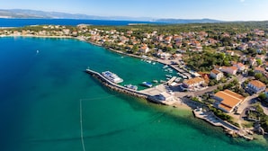 Vista aérea de uma vila costeira com um porto de iates, casas e águas azuis cristalinas.