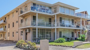 A multi-story building with balconies, large windows, and a staircase leading to an upper level. - Popular North Cronulla Beach Apartment sleeps up to 5 people (Cronulla)