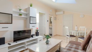 A modern living room with a flat-screen TV, a dining table with chairs, a sofa, and a skylight. - House Horizon by Interhome (Pićan)