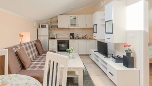 A compact living space with a kitchenette, a dining area, a sofa, and a TV. - House Horizon by Interhome (Pićan)