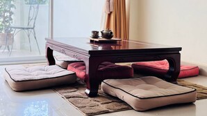 A room with a dark wooden table, cushioned seating, and a view through a large window. - Japanese Styled Condo in the Heart of Pattaya next to Pattaya Beach. (Pattaya City)