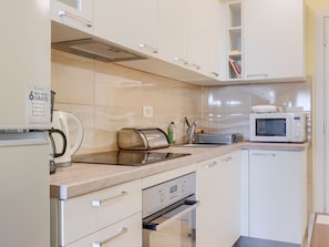 Eine moderne Küche mit weißen Schränken, einer Mikrowelle, einem Toaster und einem Spülbecken.