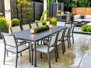 Une terrasse extérieure avec une table à manger, des chaises et un téléviseur.