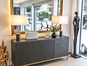 A modern living room with a dark grey console, two wall-mounted lamps, a decorative vase, and a sculpture.
