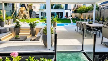 A modern outdoor patio with a pool, seating, and a children's play area.