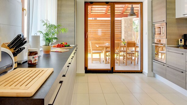 Eine moderne Küche mit Holzarbeitsplatte, integriertem Backofen und einer Glastür zum Essbereich im Freien.